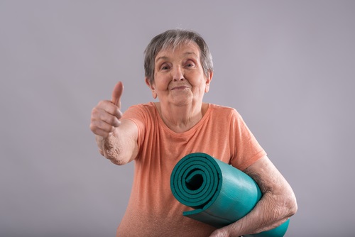 Happy elderly woman with yoga mat