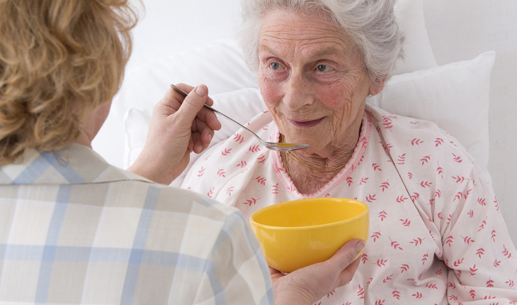 caregiver feeding elderly woman