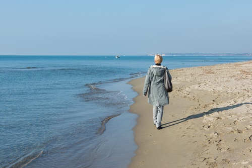 mature woman walking on beach in winter