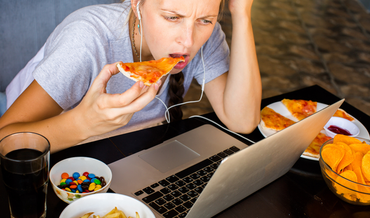 woman unhealthy eating by her laptop