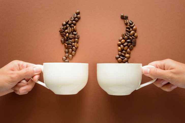 Two hands with coffee cups and beans