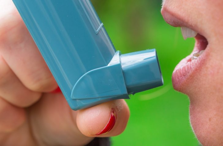 woman using asthma inhaler