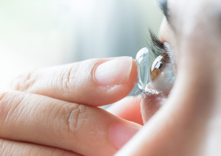 a woman putting a contact lens in her eye