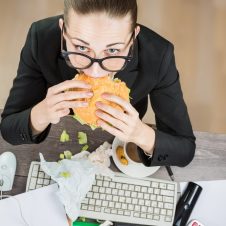 woman-eating-junk-food-at-desk